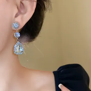 Detailed close-up showing elegant pear-shaped crystal drop earrings on a model