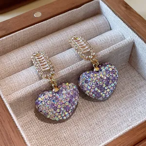 Boucles d'oreilles pendantes en forme de cœur violet strass dans un coffret cadeau en bois.