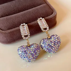 Gros plan de boucles d'oreilles cœur en strass violets étincelants avec détails zircon