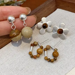 Close-up of retro beaded silver earrings set with marbled stone and flower designs