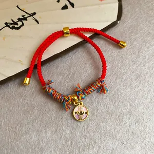 Bracelet cordon rouge fait main avec pendentif porte-bonheur doré et accents colorés
