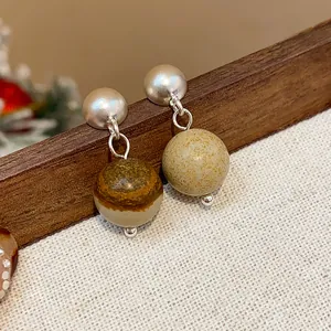 Macro detail of vintage silver stud earrings with earthy tone round beads