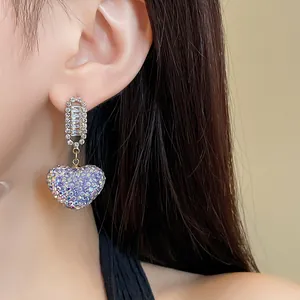 Gros plan détaillé d'une boucle d'oreille cœur pailletée violette avec zircon à l'oreille