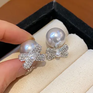 Close-up of French vintage bowknot pearl earrings with sparkling rhinestones and luster.