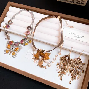 Close-up of vintage jewelry set featuring butterfly and flower pendant necklaces