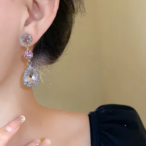 Detail view of elegant pink water drop rhinestone dangling earrings worn by an Asian model