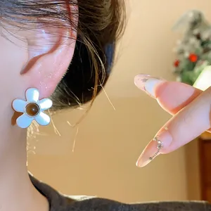 Close-up view of retro flower stud earrings with white petals and brown bead center