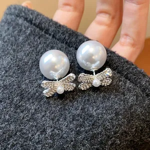 Detail of French retro bow pearl earrings with sparkly diamond inlay and high luster.