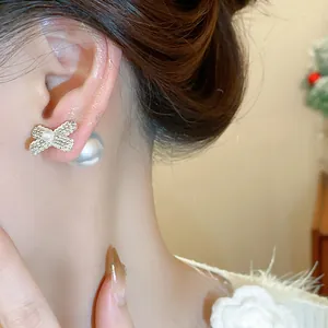 Close-up of elegant bow-knot pearl earrings worn on ear, featuring pavé-set crystals.