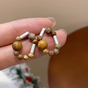 Detailed view of vintage-style beaded hoop earrings with silver needles and earth-tone beads