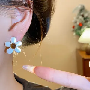 Close-up of elegant white flower stud earring with brown bead center worn for a retro look