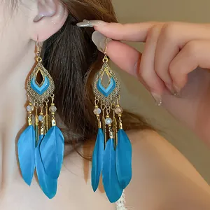 Vista detallada de pendientes largos bohemios con plumas azules y esmalte geométrico