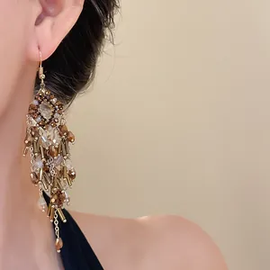 Elegant gold-toned chandelier earrings with brown crystal bead tassels on a model
