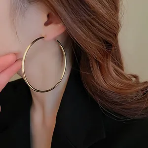 Exaggerated large gold open hoop earrings with a minimalist chic metal style look.