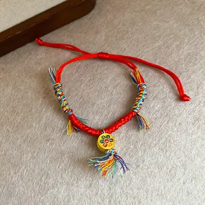 Bracelet rouge tressé année du serpent avec glands colorés et breloque dorée