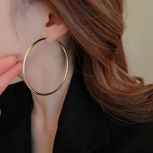 Detailed close-up of large gold open hoop earrings on model showing retro metallic style