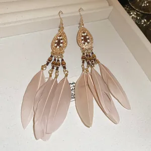 Close-up of bohemian long feather drop earrings with delicate bead and metal details