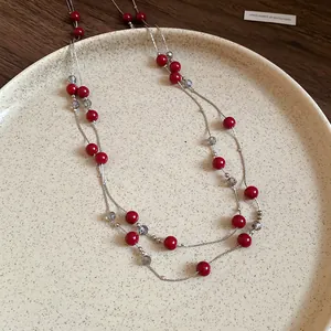Close-up of elegant double-strand sweater necklace with vibrant red and grey beads