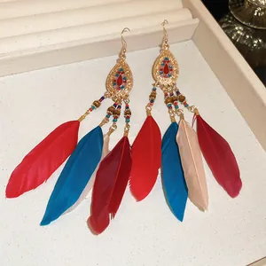 Detail view of Bohemian long feather earrings with vibrant red and blue tassels.