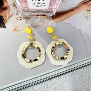 Modern geometric drop earrings with yellow circular studs and white wavy rings
