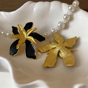 Vintage-style black enamel flower earrings with textured gold petals and silver pins