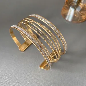 Elegant gold multi-layer open cuff bracelet with a sparkling and textured finish.