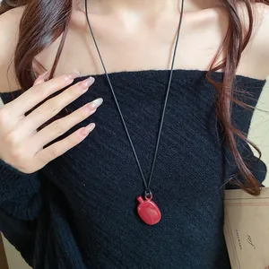 Close-up detail of a vintage red jug pendant necklace with black cord for women