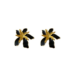 Vintage black enamel flower stud earrings with gold-toned petals and silver needles