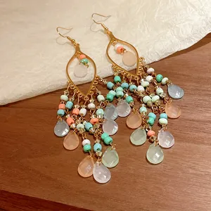 Detalle de pendientes largos bohemios con cuentas de colores y gotas de cristal
