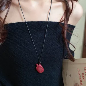 Detail view of a vintage red water bottle pendant necklace on a black leather cord
