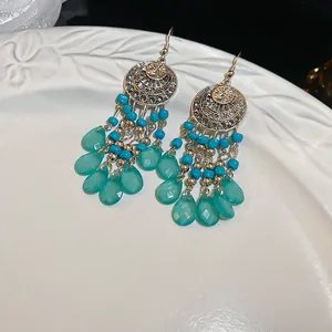 Vista detallada de pendientes bohemios de plata con cuentas turquesas y dijes de hoja