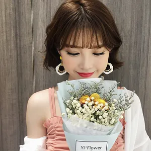 Close-up of elegant white geometric dangle earrings worn by a model with a flower bouquet