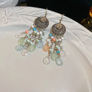 Primer plano de pendientes vintage bohemios con cuentas de colores y piedras de gota