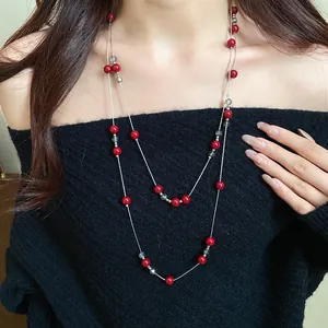 Detail view of a double-layer long necklace with elegant red and clear beads.