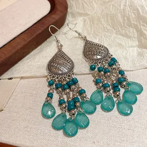 Vista detallada de pendientes largos bohemios con cuentas turquesas y colgantes de gota.