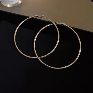 Detailed macro view of minimalist extra large silver hoop earrings on premium black velvet
