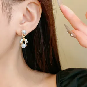 Detailed view of elegant gold-tone earrings featuring faux pearls and sparkling rhinestones
