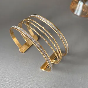 Detail view of an elegant multi-layer gold open bangle with glitter finish for women.