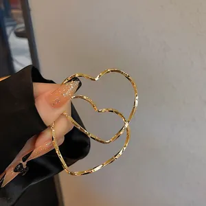 Nahaufnahme übergroßer herzförmiger goldener Creolen mit gedrehter Metallstruktur für Damen