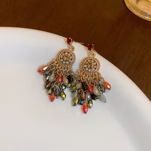 Primer plano de pendientes largos bohemios con cuentas de colores sobre marco dorado