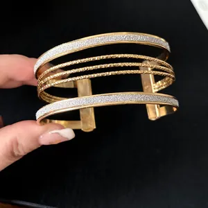 Detailed macro view of layered gold cuff bracelet with silver glitter finish