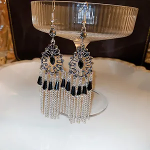Primer plano de pendientes bohemios vintage con piedras negras y borlas de cadena larga