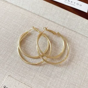 Detailed view of elegant gold double-layer hoop earrings displayed on a textured surface