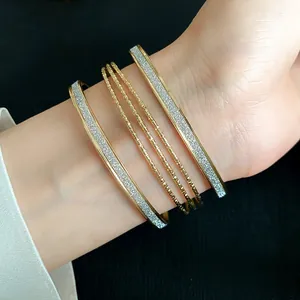 Close-up of elegant gold multi-layer bangles with silver glitter inlay on female wrist