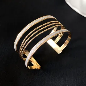 Close-up of elegant gold-toned multi-layer cuff bracelet with glitter and textured finish.