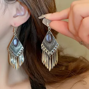 Detalle de pendientes bohemios vintage plateados con cabujón azul y colgantes metálicos