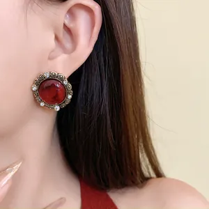 Dettaglio di un orecchino rotondo vintage in resina rossa con decorazioni in strass