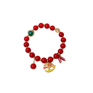 Elegant red beaded bracelet featuring a delicate golden rocking horse pendant for women