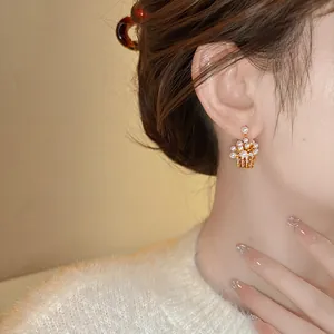 Close-up of elegant flower basket earrings with pearls and cubic zirconia on model's ear