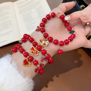 Detailed view of red beaded bracelet with gold horse charms for women and zodiac luck.